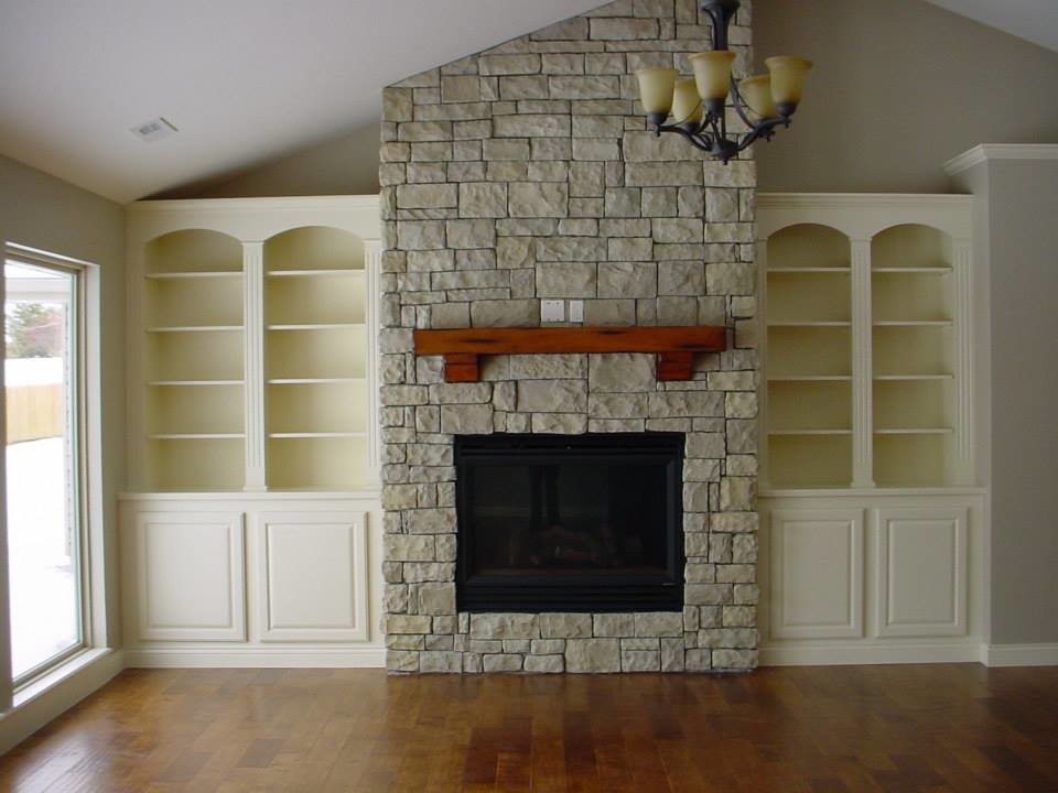 Medium tone wood floor living room photo with beige walls, a standard fireplace, a stone fireplace and no tv
