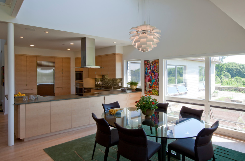 This is an example of a contemporary kitchen/dining combo in Portland Maine with white walls and light hardwood floors.