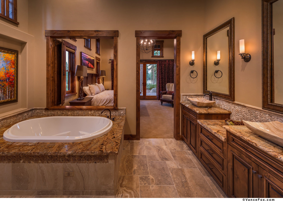 Large traditional master bathroom in Sacramento with raised-panel cabinets, medium wood cabinets, granite benchtops, a drop-in tub, a corner shower, a one-piece toilet, brown tile, stone tile, beige walls, travertine floors and a vessel sink.