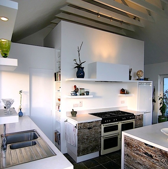 This is an example of a contemporary eat-in kitchen in Other with a drop-in sink, flat-panel cabinets, distressed cabinets, concrete benchtops, white splashback, cement tile splashback, coloured appliances, slate floors, with island and white benchtop.