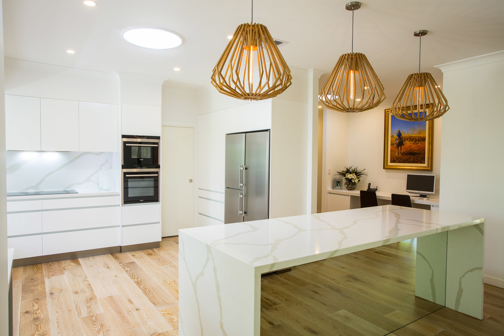 Inspiration for an expansive contemporary u-shaped kitchen pantry in Brisbane with a single-bowl sink, flat-panel cabinets, white cabinets, quartz benchtops, white splashback, stone slab splashback, stainless steel appliances, light hardwood floors and with island.