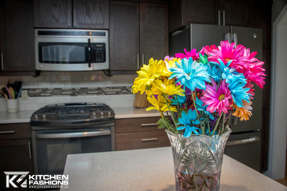 Mid-sized transitional l-shaped enclosed kitchen photo in Toronto with an undermount sink, shaker cabinets, dark wood cabinets, quartz countertops, multicolored backsplash, subway tile backsplash, stainless steel appliances and an island