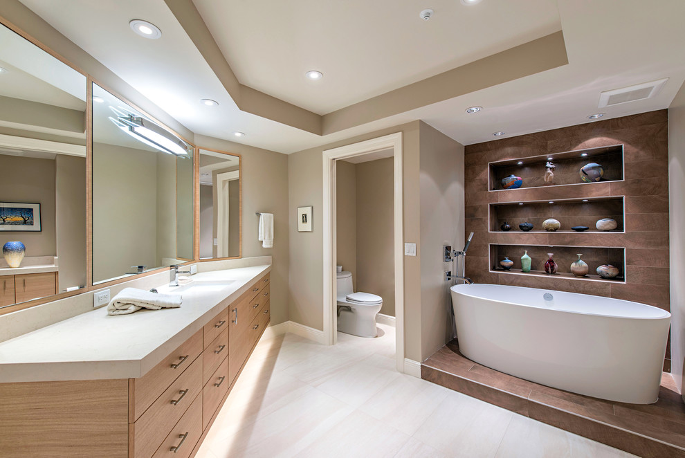 Photo of a contemporary master bathroom in Minneapolis with flat-panel cabinets, light wood cabinets, beige benchtops, a freestanding tub, beige walls, an undermount sink and beige floor.