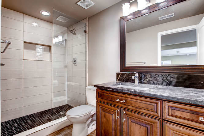 Photo of a mid-sized transitional 3/4 bathroom in Denver with raised-panel cabinets, brown cabinets, an alcove shower, a two-piece toilet, white tile, porcelain tile, grey walls, ceramic floors, an undermount sink, onyx benchtops, brown floor and an open shower.