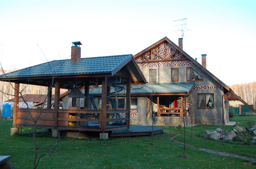 Ejemplo de fachada de casa gris y azul contemporánea grande de tres plantas con revestimiento de piedra, tejado a dos aguas, tejado de teja de barro y tablilla