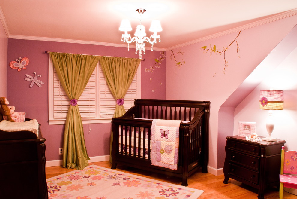 Contemporary nursery in New York with pink walls and medium hardwood floors for girls.