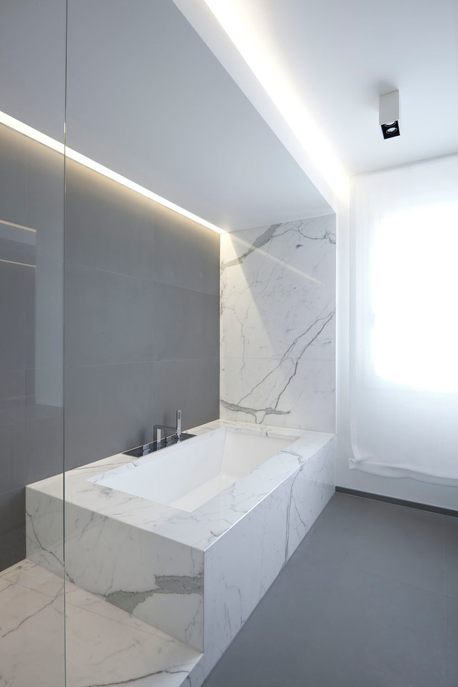 Inspiration for a contemporary master bathroom in Venice with a drop-in tub, stone slab, grey walls and porcelain floors.