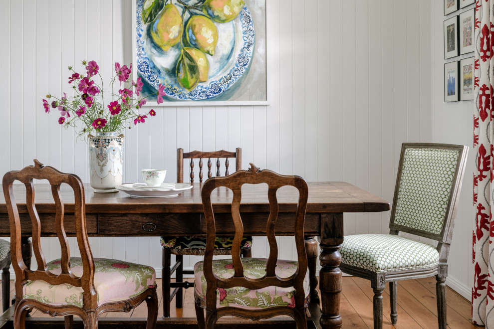 Foto di una sala da pranzo country con pareti bianche, pavimento in legno massello medio, pavimento marrone e pareti in perlinato