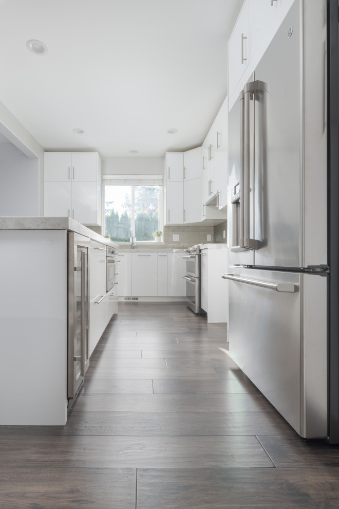 シアトルにある高級な広いコンテンポラリースタイルのおしゃれなキッチン (フラットパネル扉のキャビネット、白いキャビネット、大理石カウンター、白いキッチンパネル、レンガのキッチンパネル、シルバーの調理設備、濃色無垢フローリング、マルチカラーの床、白いキッチンカウンター) の写真