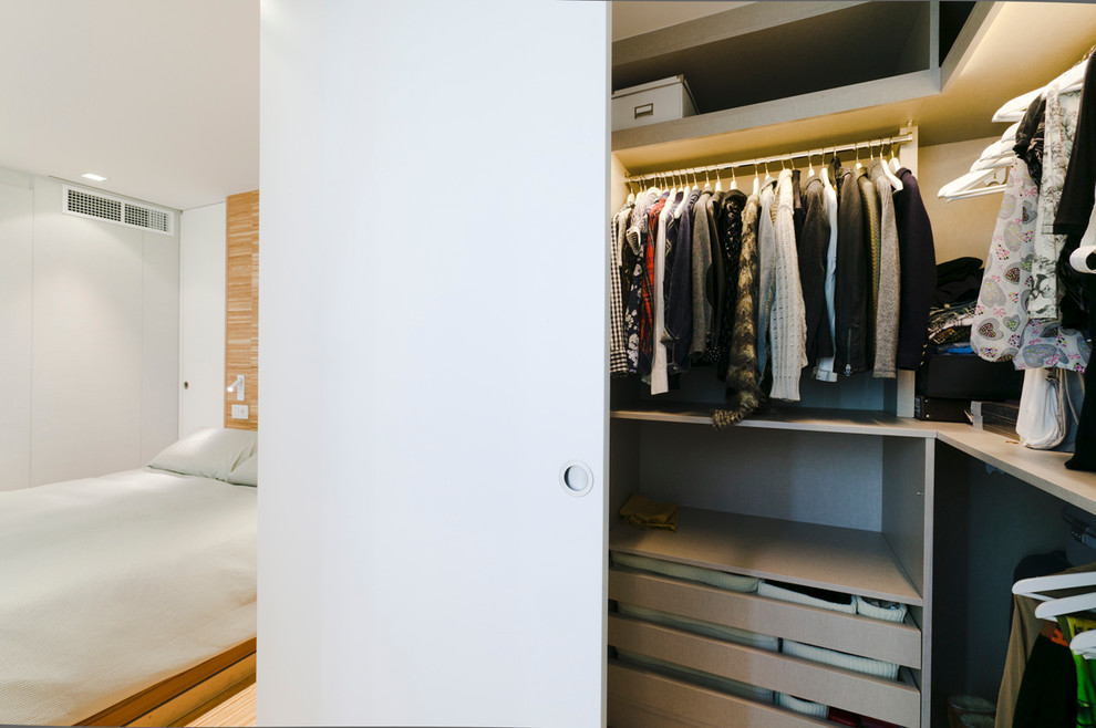 Mid-sized contemporary gender-neutral built-in wardrobe in Barcelona with flat-panel cabinets and white cabinets.
