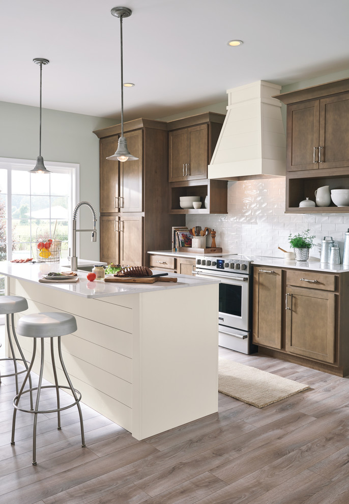 Inspiration for a country kitchen in Other with shaker cabinets, medium wood cabinets, white splashback, subway tile splashback, stainless steel appliances, medium hardwood floors, with island, brown floor and white benchtop.