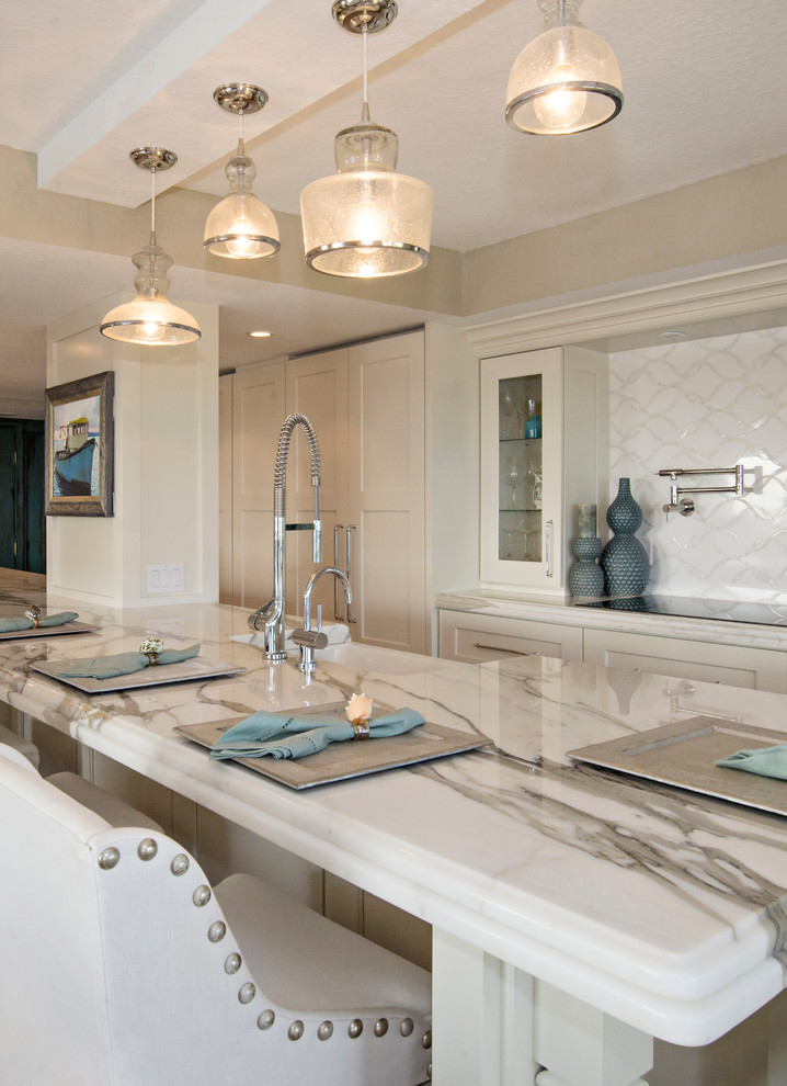 Inspiration for a large beach style galley open plan kitchen in Orlando with a double-bowl sink, glass-front cabinets, white cabinets, marble benchtops, white splashback, stone slab splashback, stainless steel appliances and light hardwood floors.