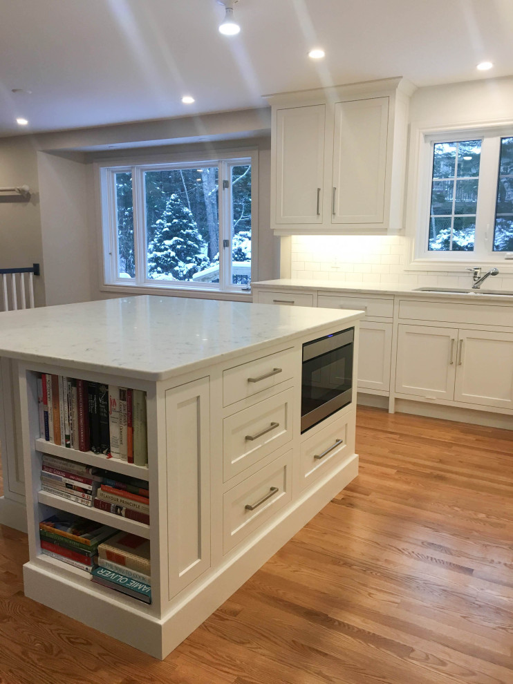 Large transitional u-shaped light wood floor and beige floor eat-in kitchen photo with a double-bowl sink, shaker cabinets, white cabinets, quartzite countertops, white backsplash, subway tile backsplash, stainless steel appliances, an island and white countertops
