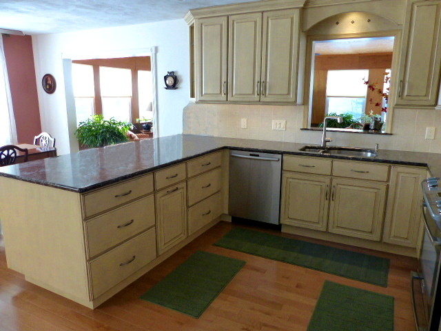Mid-sized mountain style u-shaped light wood floor eat-in kitchen photo in New York with an undermount sink, raised-panel cabinets, beige cabinets, quartz countertops, ceramic backsplash, stainless steel appliances, a peninsula and beige backsplash
