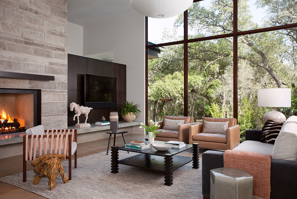 Design ideas for a contemporary living room in Austin with white walls, dark hardwood floors, a standard fireplace, a stone fireplace surround, a wall-mounted tv and brown floor.