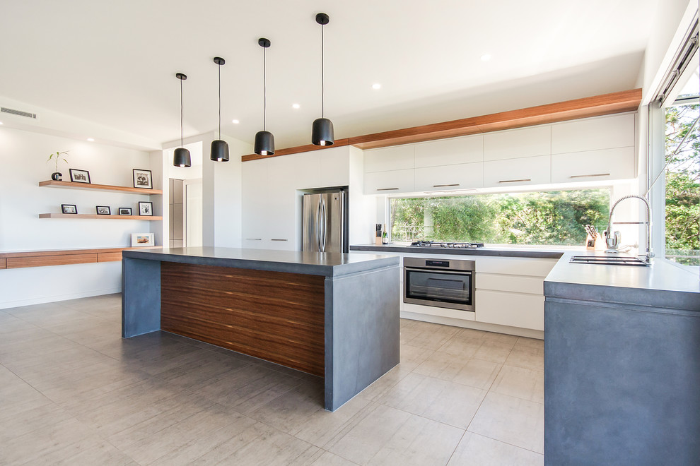 This is an example of a mid-sized modern kitchen pantry in Sunshine Coast with a farmhouse sink, white cabinets, concrete benchtops, window splashback, stainless steel appliances, porcelain floors, with island and beige floor.