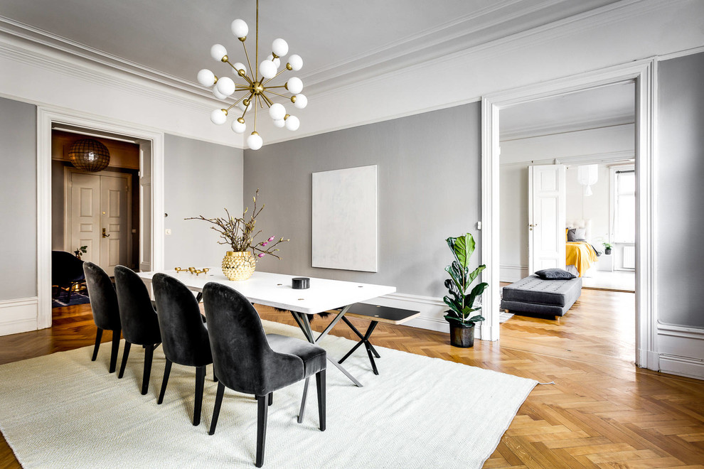 This is an example of a large scandinavian separate dining room in Stockholm with grey walls and light hardwood floors.