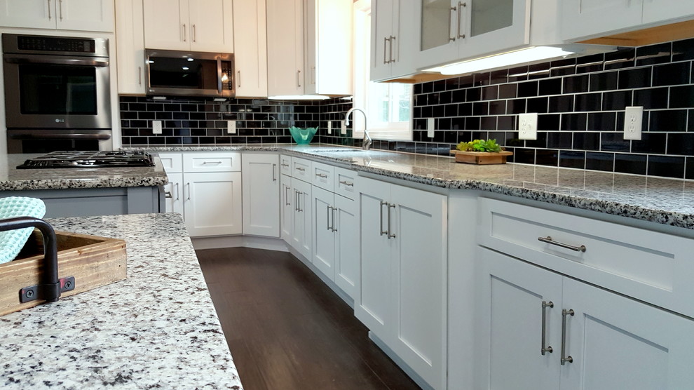 Inspiration for a large transitional l-shaped dark wood floor and brown floor eat-in kitchen remodel with an undermount sink, shaker cabinets, white cabinets, granite countertops, black backsplash, ceramic backsplash, stainless steel appliances and two islands