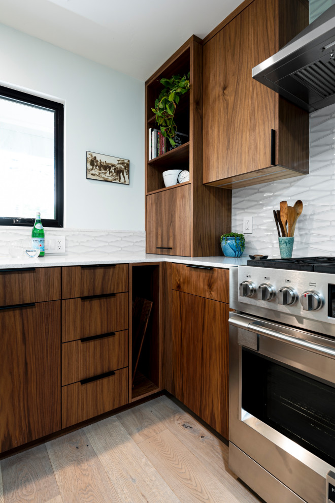 Inspiration for a mid-sized midcentury l-shaped eat-in kitchen in Sacramento with a farmhouse sink, flat-panel cabinets, dark wood cabinets, quartz benchtops, white splashback, porcelain splashback, stainless steel appliances, light hardwood floors, with island, brown floor and white benchtop.