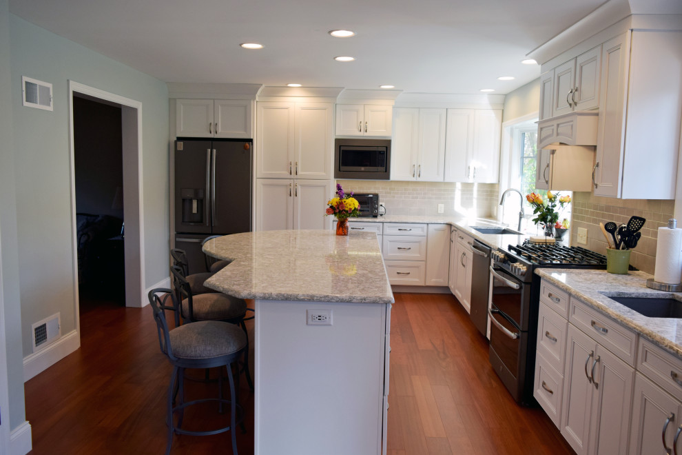 Inspiration for a transitional medium tone wood floor kitchen remodel with an undermount sink, recessed-panel cabinets, white cabinets, quartz countertops, gray backsplash, subway tile backsplash, stainless steel appliances and an island