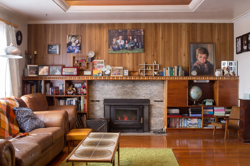 Photo of a midcentury living room in Hobart with red walls, medium hardwood floors, a wood stove and a metal fireplace surround.