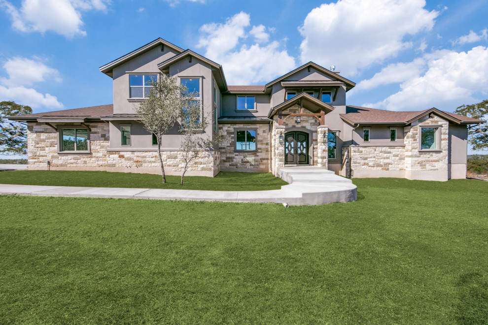 Photo of a large arts and crafts two-storey multi-coloured house exterior in Austin with stone veneer, a gable roof, a mixed roof and a brown roof.