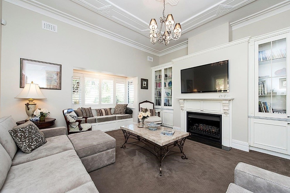 Photo of a mid-sized traditional formal enclosed living room in Perth with beige walls, carpet, a standard fireplace, a plaster fireplace surround and a wall-mounted tv.