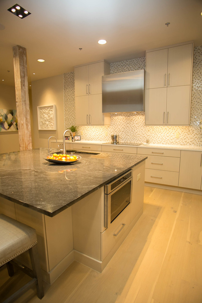 Kitchen - mid-sized transitional l-shaped light wood floor kitchen idea in New Orleans with an undermount sink, flat-panel cabinets, beige cabinets, multicolored backsplash, mosaic tile backsplash, stainless steel appliances and an island
