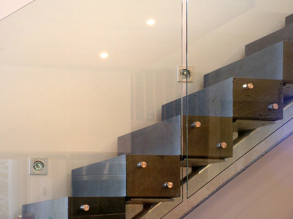 Photo of a large contemporary l-shaped staircase in Other with glass railing.