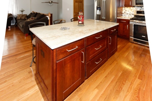 Example of a mid-sized transitional l-shaped medium tone wood floor eat-in kitchen design in Chicago with an undermount sink, recessed-panel cabinets, medium tone wood cabinets, granite countertops, gray backsplash, glass tile backsplash, stainless steel appliances, beige walls and an island
