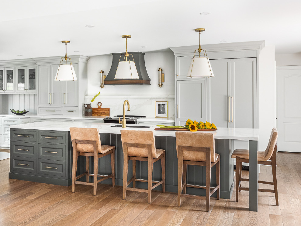 Design ideas for a transitional galley eat-in kitchen in Toronto with an undermount sink, recessed-panel cabinets, grey cabinets, quartz benchtops, white splashback, engineered quartz splashback, panelled appliances, medium hardwood floors, with island, brown floor and white benchtop.