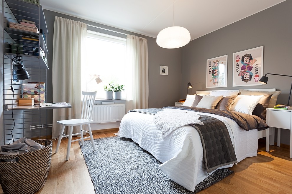 Large scandinavian master bedroom in Gothenburg with grey walls, medium hardwood floors, no fireplace and brown floor.