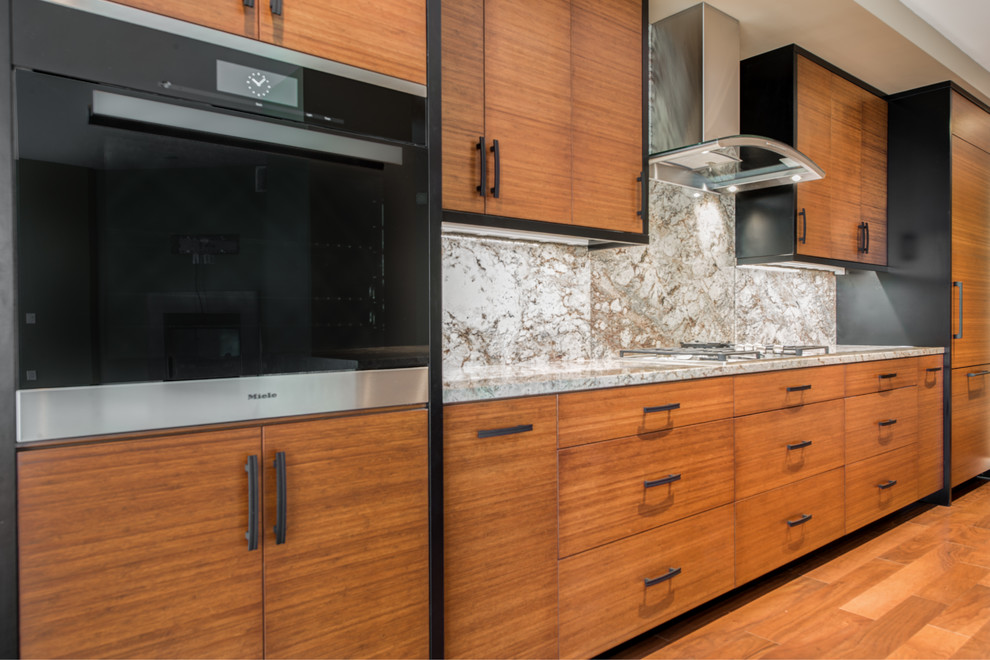 Inspiration for a mid-sized contemporary galley open plan kitchen in Seattle with an undermount sink, flat-panel cabinets, medium wood cabinets, granite benchtops, stone slab splashback, panelled appliances, medium hardwood floors and with island.