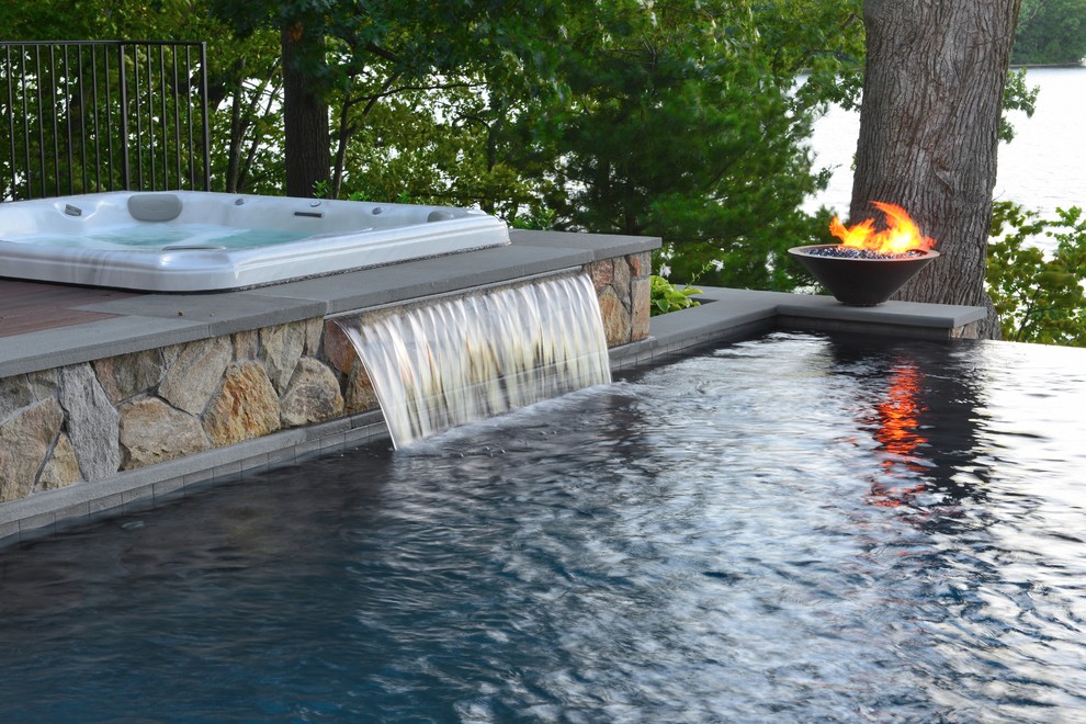 Inspiration for a mid-sized contemporary backyard rectangular infinity pool in New York with a water feature and natural stone pavers.