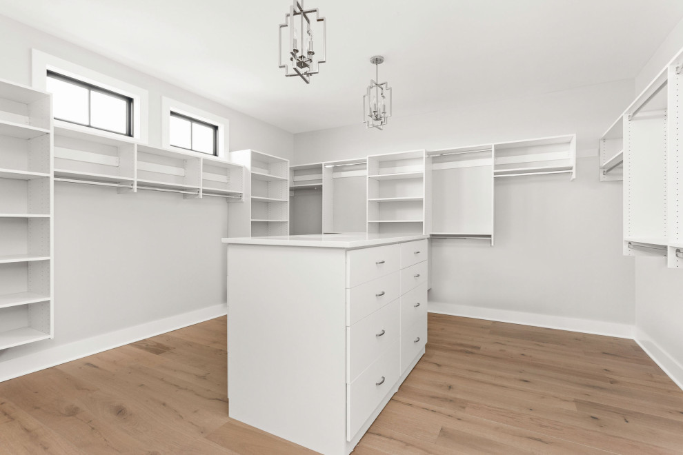 Design ideas for a large modern gender neutral built-in wardrobe in Indianapolis with flat-panel cabinets, white cabinets, light hardwood flooring and multi-coloured floors.