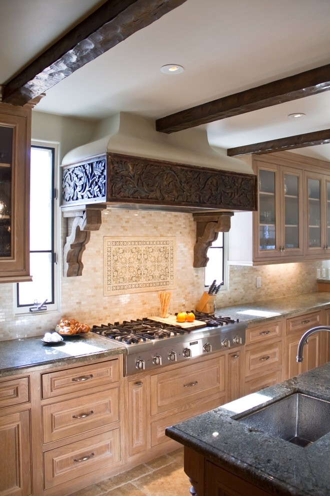 Country kitchen in Los Angeles with stainless steel appliances, medium wood cabinets, granite benchtops, beige splashback and stone tile splashback.