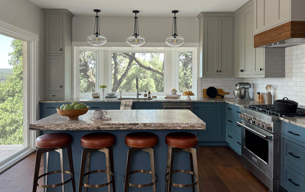 Example of a transitional l-shaped dark wood floor and brown floor kitchen design in Austin with an undermount sink, shaker cabinets, blue cabinets, white backsplash, subway tile backsplash, stainless steel appliances, an island and gray countertops