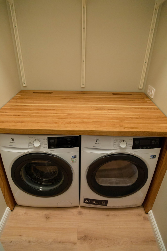 Immagine di una piccola sala lavanderia nordica con top in legno, pareti grigie, pavimento in vinile e lavatrice e asciugatrice affiancate