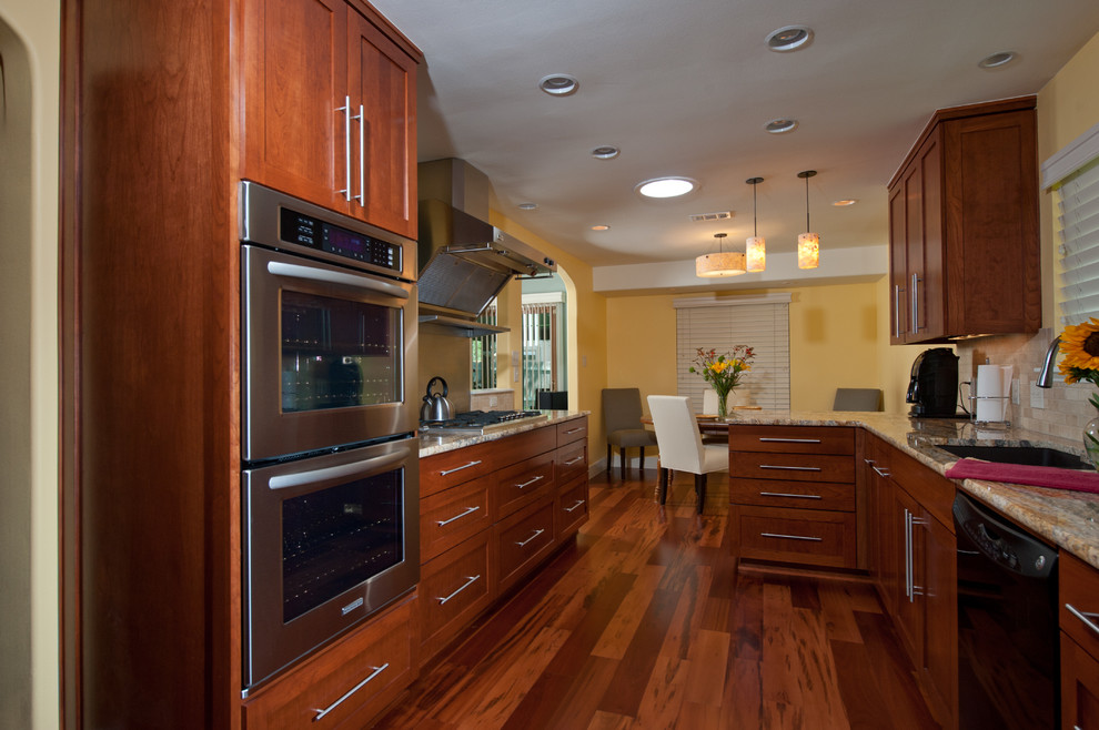 Eat-in kitchen - transitional galley medium tone wood floor eat-in kitchen idea in Austin with an undermount sink, recessed-panel cabinets, medium tone wood cabinets, granite countertops, beige backsplash, ceramic backsplash, stainless steel appliances, yellow walls and no island