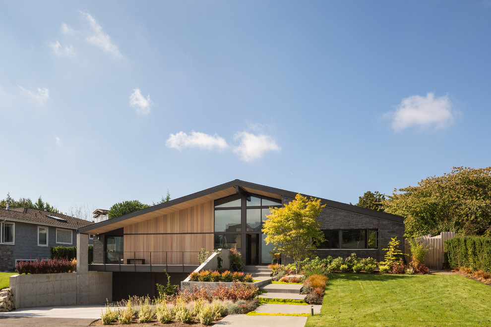 Large 1950s black two-story brick gable roof idea in Seattle