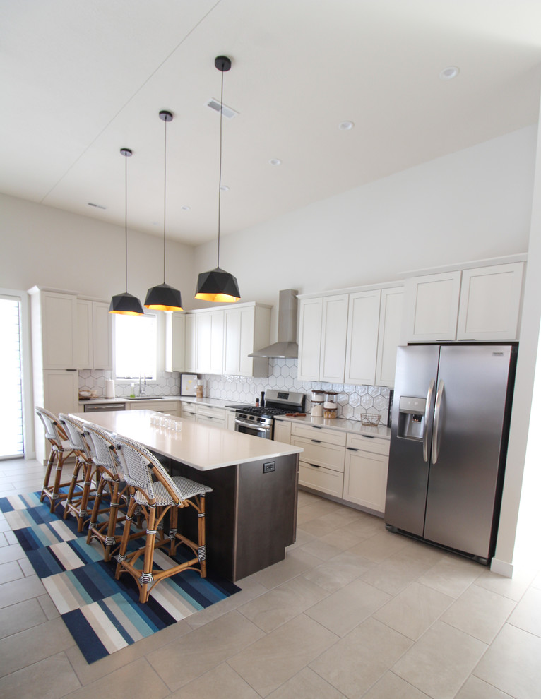 Porcelain tile open concept kitchen photo with an undermount sink, shaker cabinets, white cabinets, quartz countertops, white backsplash, stainless steel appliances, an island and white countertops