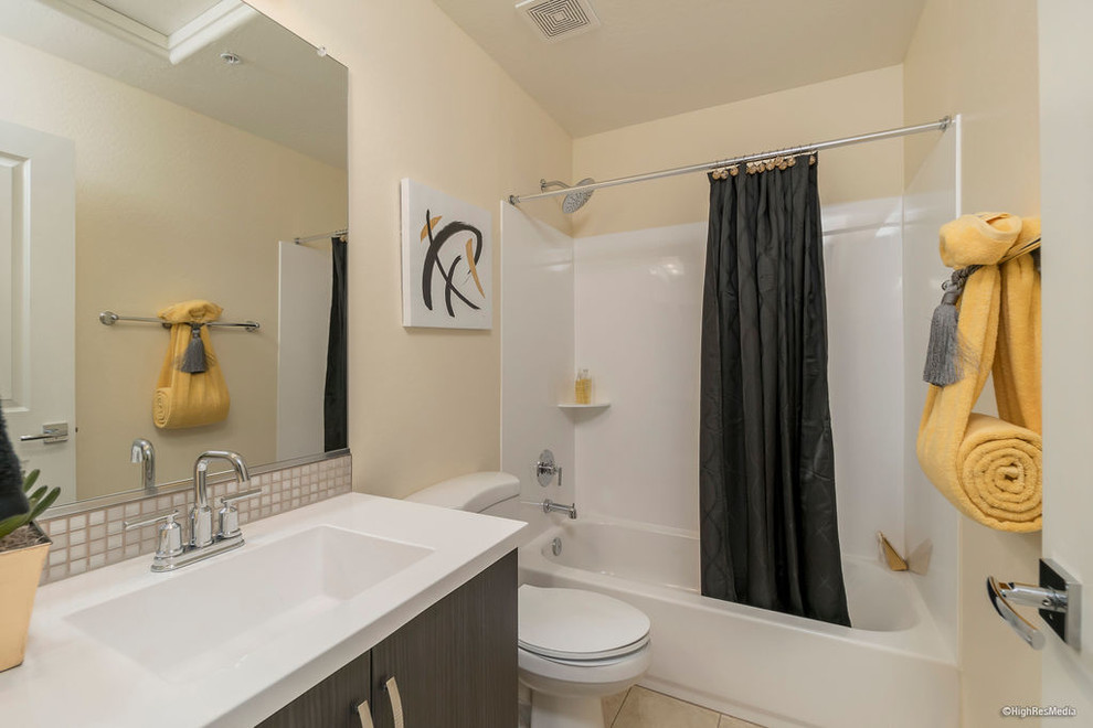 Example of a mid-sized transitional master beige tile and porcelain tile porcelain tile and beige floor alcove bathtub design in Phoenix with flat-panel cabinets, dark wood cabinets, a two-piece toilet, beige walls, an integrated sink, quartz countertops and white countertops