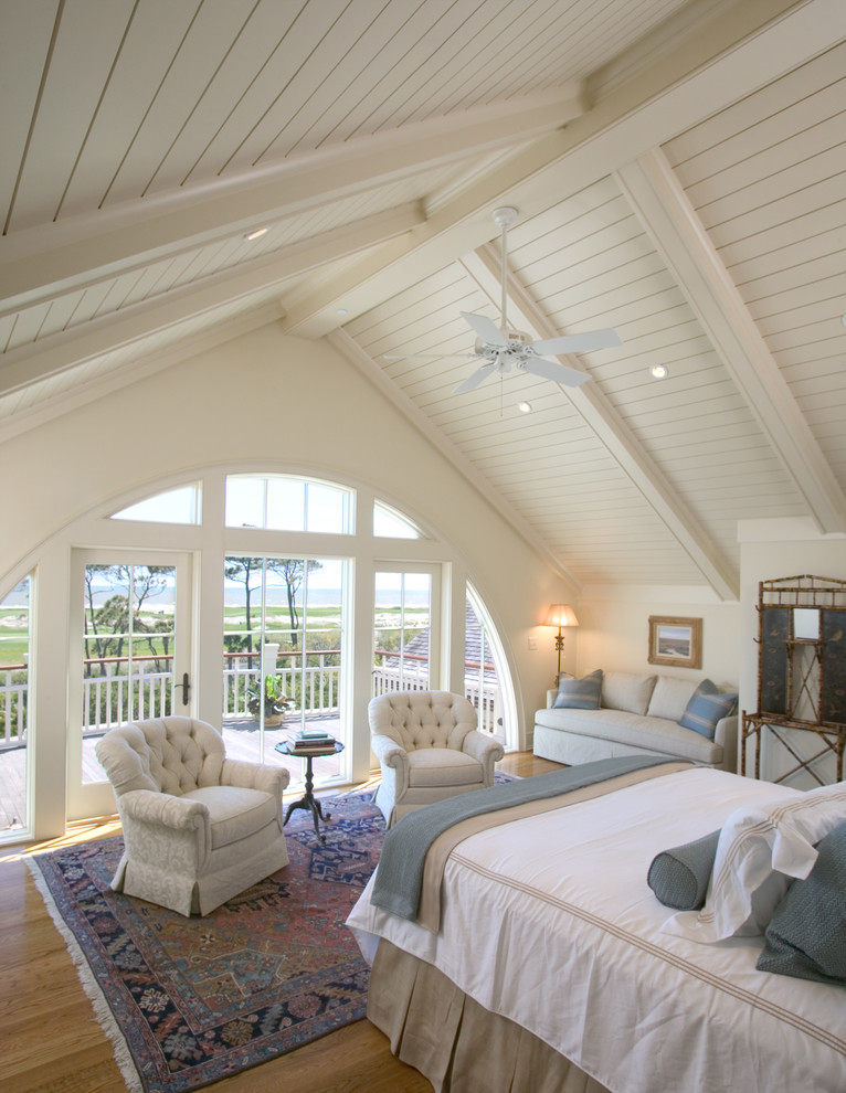 Photo of a mid-sized beach style master bedroom in Charleston with beige walls and medium hardwood floors.