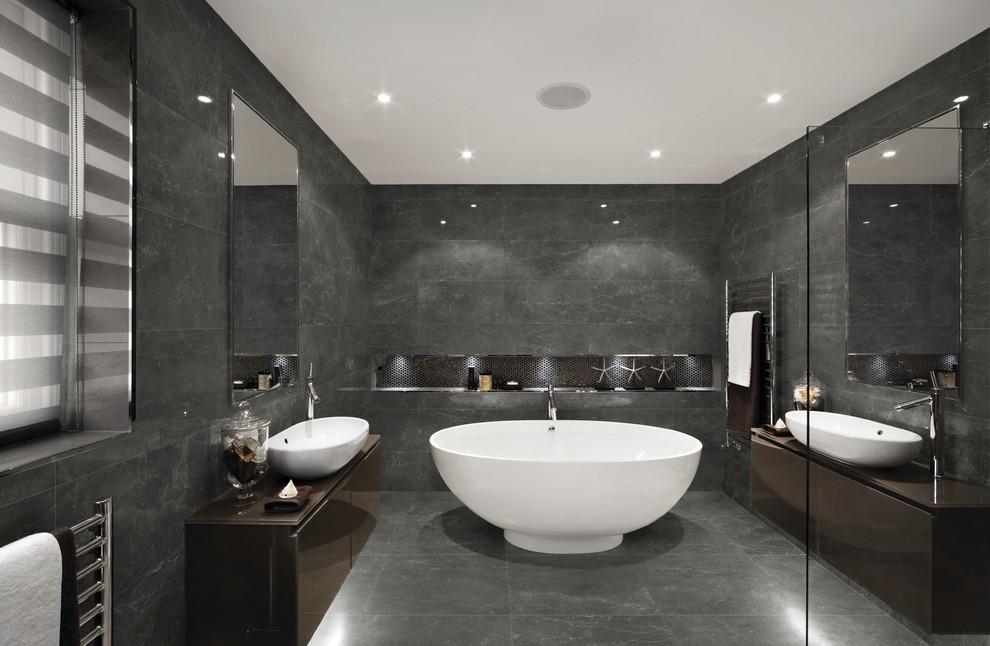 This is an example of a contemporary master bathroom in Philadelphia with flat-panel cabinets, brown cabinets, a freestanding tub, gray tile, grey walls, a vessel sink and grey floor.