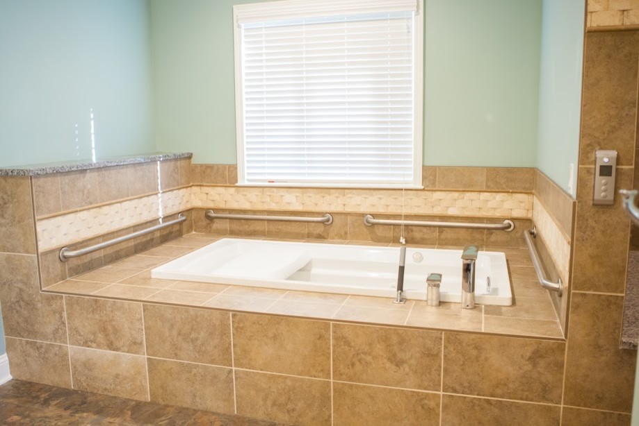Photo of a mid-sized traditional bathroom in Other with raised-panel cabinets, dark wood cabinets, a drop-in tub, beige tile, ceramic tile, green walls, linoleum floors, a drop-in sink and brown floor.