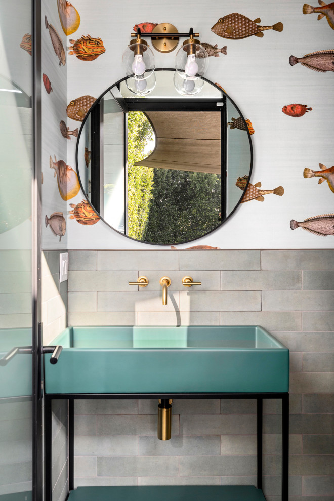 This is an example of a mid-sized beach style 3/4 bathroom in Los Angeles with open cabinets, turquoise cabinets, an alcove shower, a one-piece toilet, gray tile, cement tile, white walls, cement tiles, a vessel sink, glass benchtops, white floor, a hinged shower door, turquoise benchtops, a niche, a single vanity and a freestanding vanity.