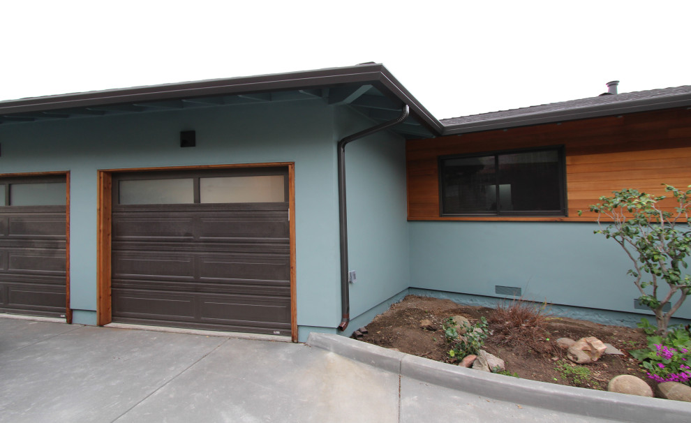 Mid-sized transitional one-storey stucco blue house exterior in Other with a shingle roof.