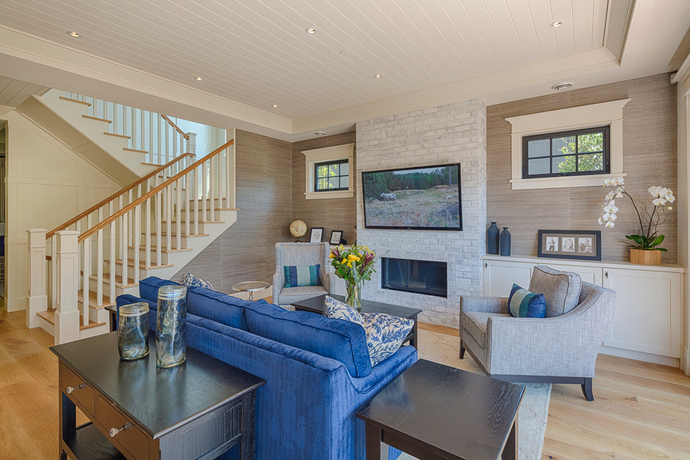 Inspiration for a mid-sized arts and crafts open concept family room in Vancouver with beige walls, light hardwood floors, a standard fireplace, a brick fireplace surround and a wall-mounted tv.