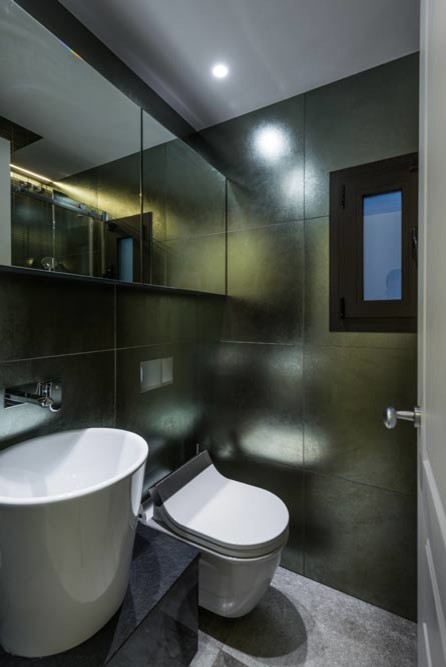Modelo de aseo minimalista pequeño con sanitario de una pieza, paredes negras, suelo de baldosas de porcelana, lavabo sobreencimera y suelo gris