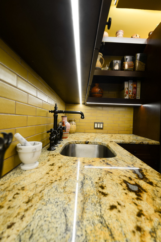 Photo of a mid-sized single-wall open plan kitchen in New York with an undermount sink, recessed-panel cabinets, dark wood cabinets, quartzite benchtops, yellow splashback, subway tile splashback, stainless steel appliances, terra-cotta floors, with island, orange floor and multi-coloured benchtop.